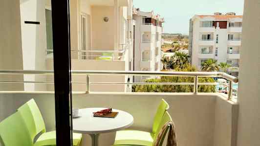 Bilde av en balkong med bord og stoler samt utsikt over omkringliggende bygninger. (AI-generert tekst)