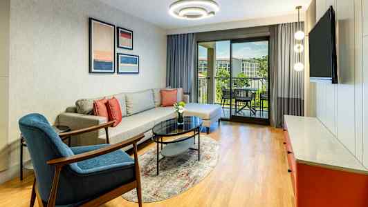 En stue med sofa, lenestol, salongbord og utsikt mot en balkong. (AI-generert tekst)