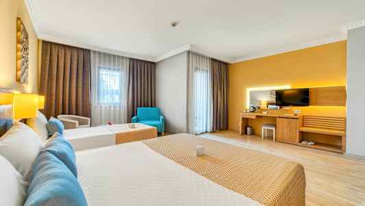 Et hotellrom med to senger, en skrivebordkrok med TV og store vinduer med gardiner. (AI-generert tekst)