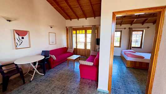 Stue med røde sofaer og tremøbler samt et tilknyttet soverom. (AI-generert tekst)