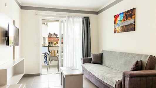 En lys stue med sofa, bord og åpen balkong. (AI-generert tekst)