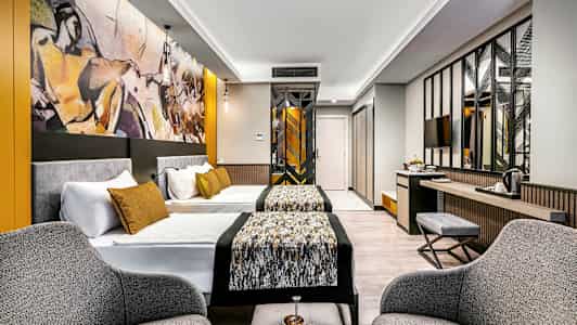 Moderne hotellrom med to senger, sittegruppe og kunst på veggen. (AI-generert tekst)