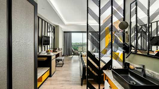 Bilde av et moderne hotellrom med skrivebord, stol og TV samt en separat sovedel. (AI-generert tekst)