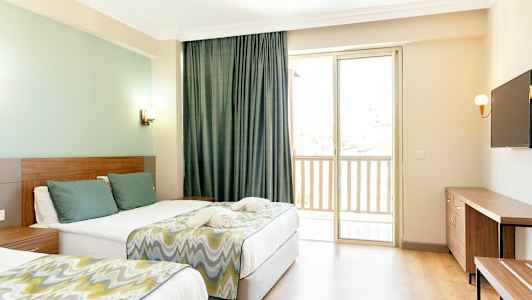 Et hotellrom med to senger, en TV på veggen og et vindu med balkong. (AI-generert tekst)