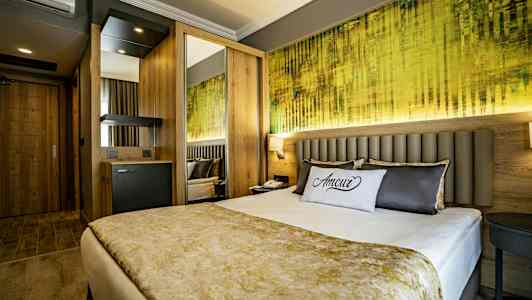 Et moderne hotellrom med en dobbeltseng, dekorativ pute og fargerik veggkunst. (AI-generert tekst)