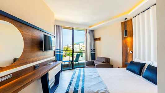 Hotellrom med seng, lenestol, TV og balkong med utsikt. (AI-generert tekst)