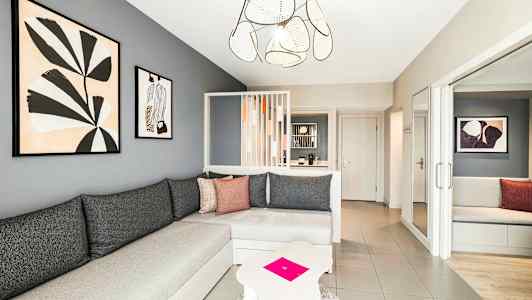 En moderne stue med grå vegger, en hjørnesofa og kunst på veggen. (AI-generert tekst)