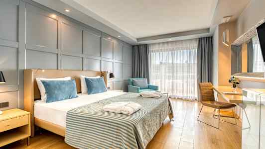 Hotellrom med en dobbeltseng, to lenestoler og et skrivebord. (AI-generert tekst)