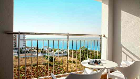 Utsikt fra en balkong med to moderne stoler, et bord og havet i bakgrunnen. (AI-generert tekst)