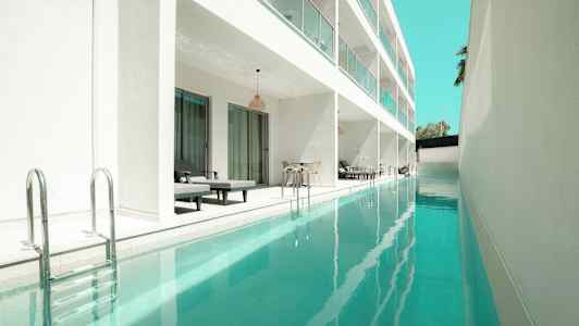 Bilde av et langt basseng ved siden av en moderne hvit bygning med private sitteplasser. (AI-generert tekst)