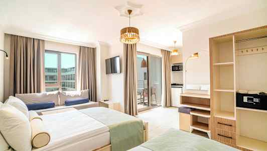 Bilde av et hotellrom med moderne møbler, to senger, en sofa, en TV og en balkong med lyse gardiner. (AI-generert tekst)