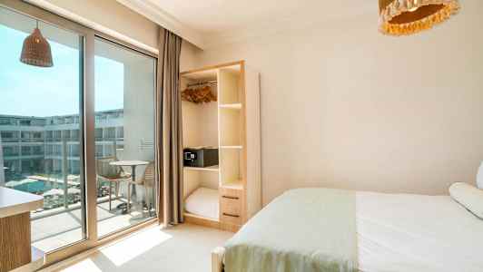 Hotellrom med seng, garderobe og balkong som vender mot et basseng. (AI-generert tekst)