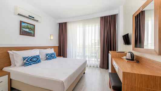 Et hotellrom med en dobbeltseng, skrivebord og balkong. (AI-generert tekst)