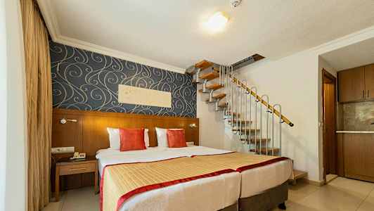 Et hotellrom med to senger, dekorativ tapet og en spiraltrapp som leder oppover. (AI-generert tekst)
