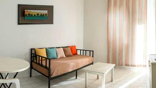 En stue med en sofa, puter i forskjellige farger, et lite bord og et bilde på veggen. (AI-generert tekst)