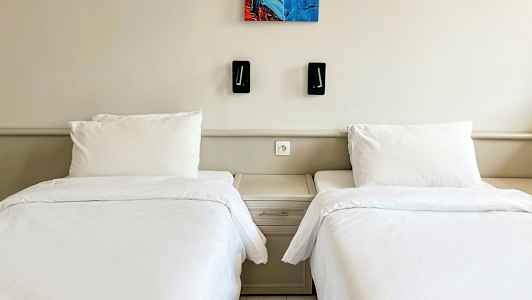 To enkeltsenger med hvitt sengetøy og et felles nattbord mellom dem. (AI-generert tekst)