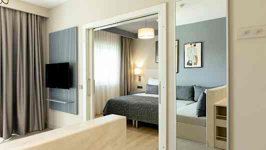 Bilde av et hotellrom med seng, speil og TV. (AI-generert tekst)