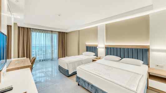 Hotellrom med to senger, skrivebord og utsikt mot balkong. (AI-generert tekst)