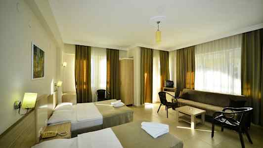 Et hotellrom med to enkeltsenger, en sofa, bord og stoler. (AI-generert tekst)