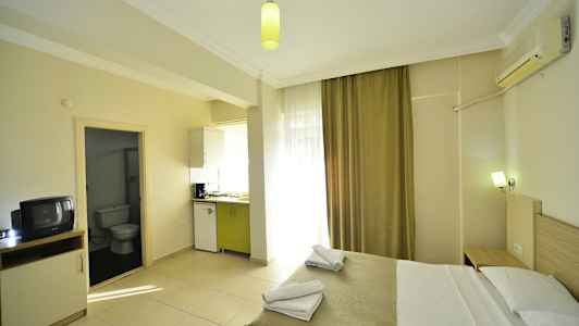 Et hotellrom med en seng, kjøkkenkrok og inngang til bad. (AI-generert tekst)