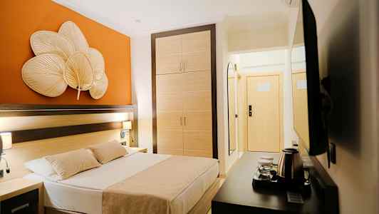 Et hotellrom med en seng, garderobe og oransje veggdekorasjon. (AI-generert tekst)