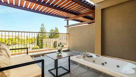 En terrasse med boblebad, sittemøbler, blomsterbukett og utsikt over grøntområder. (AI-generert tekst)