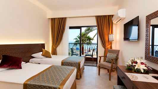 Hotellrom med to enkeltsenger, vindu med utsikt mot palmer og hav. (AI-generert tekst)