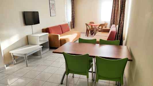 Et oppholdsrom med sofaer, et spisebord med stoler og en veggmontert TV. (AI-generert tekst)