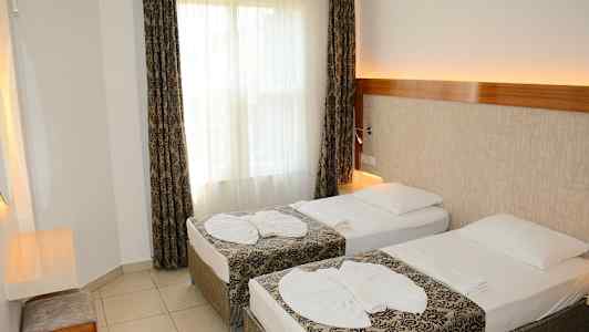 Et hotellrom med to enkeltsenger og dekorerte sengeklær. (AI-generert tekst)