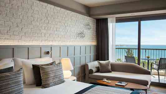 Bilde av et moderne hotellrom med havutsikt fra en balkong. (AI-generert tekst)