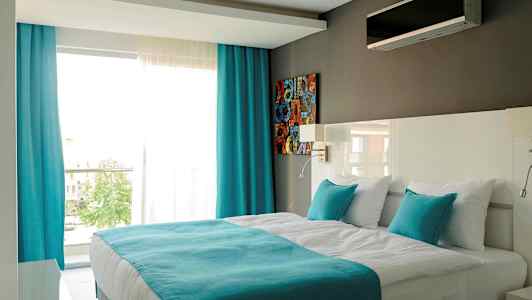 Moderne hotellrom med en dobbeltseng, hvite og turkise farger. (AI-generert tekst)