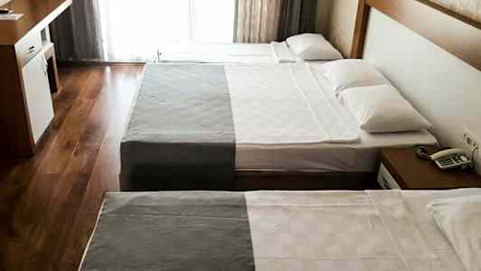 Hotellrom med to senger og et skrivebord. (AI-generert tekst)