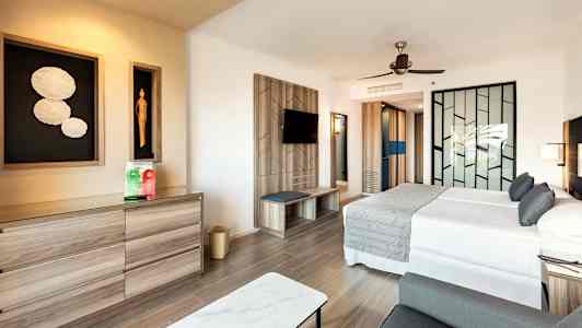 Moderne hotellrom med dobbeltseng, sittegruppe og kunst på veggen. (AI-generert tekst)