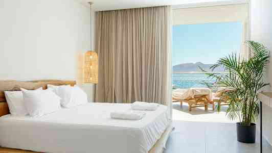 Et lyst soverom med dobbeltseng og utsikt over havet. (AI-generert tekst)