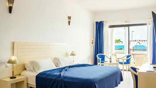 Hotellrom med seng, møbler og havutsikt. (AI-generert tekst)