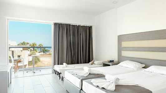 Et hotellrom med to oppredde senger og en balkong med utsikt. (AI-generert tekst)