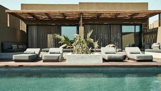 Bilde av et basseng foran en uteplass med solsenger og sofagruppe. (AI-generert tekst)