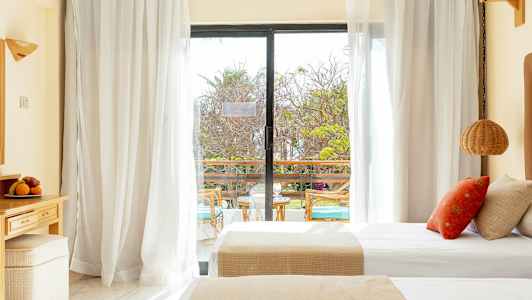 Et hotellrom med dobbeltsenger og en glassdør som fører ut til en balkong. (AI-generert tekst)