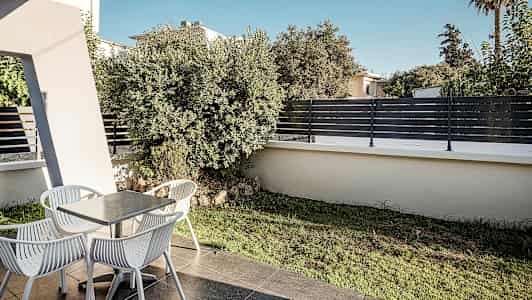 En uteplass med et bord og fire stoler, omgitt av vegetasjon og gjerde. (AI-generert tekst)