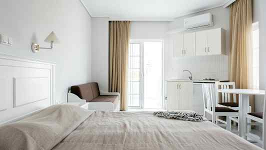 En oversikt over et hotellrom med en seng, sofa, kjøkken og spisebord. (AI-generert tekst)