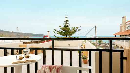 En balkong med utsikt mot havet og nærliggende bygninger. (AI-generert tekst)