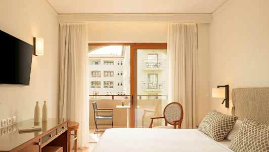 Moderne hotellrom med dobbeltseng, skrivebord, TV og balkong med utsikt. (AI-generert tekst)