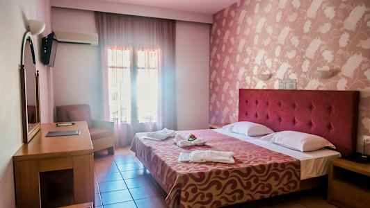 Et hotellrom med en dobbeltseng, skrivebord, lenestol og dekorert vegg. (AI-generert tekst)