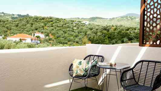 En balkong med utsikt over et grønt landskap og hus med røde tak. (AI-generert tekst)