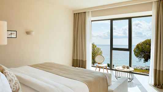 Hotellrom med havutsikt gjennom et stort vindu. (AI-generert tekst)