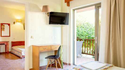 Et hotellrom med skrivebord, stol, TV og balkong med utemøbler. (AI-generert tekst)