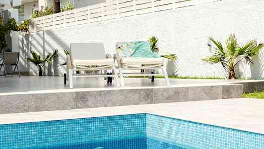 To solsenger ved et basseng med hvit bakgrunnsgrense. (AI-generert tekst)