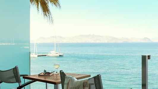 Utsikt over havet fra en terrasse med bord og stoler. (AI-generert tekst)