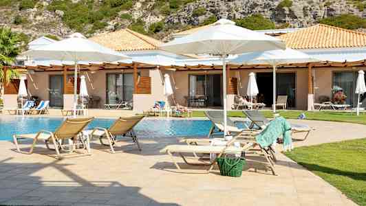 Solstoler ved et basseng foran bungalower med hage. (AI-generert tekst)