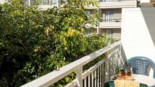 Bilde av en balkong med bord, stol og grøntområde i forgrunnen. (AI-generert tekst)